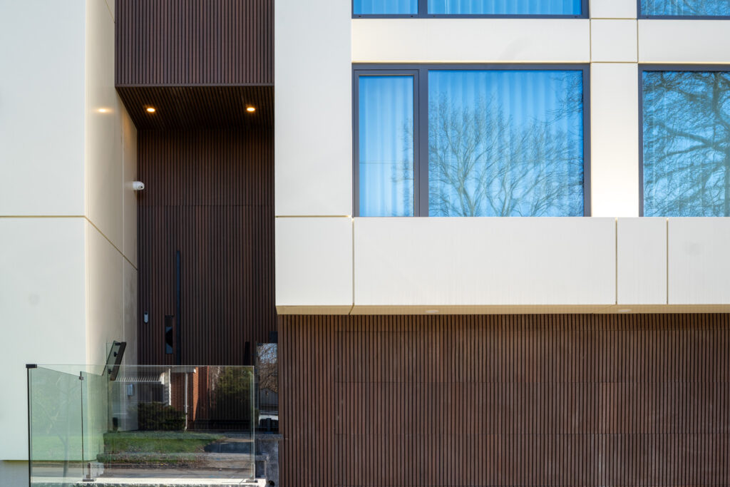 Front entrance of 23 Granlea Rd with Rosewood fluted panels, ETT Tan ACM facade panels, glass railing, and integrated garage cladding.