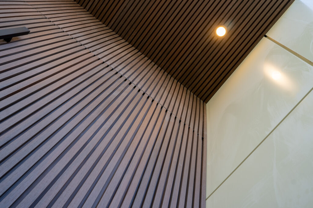 Close-up of CladMart Rosewood fluted composite panels and soffit detailing at 23 Granlea Rd with warm wood-look texture.