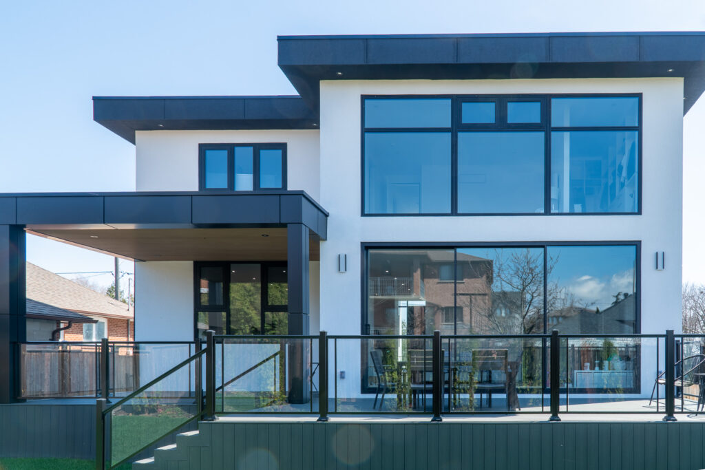 Rear elevation of 61 Deevale Rd with Creamy Cedar fluted composite panels, black ACM canopy, large glass windows, and glass railing.